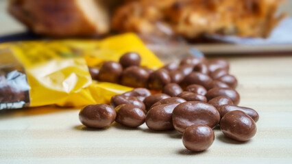 Close-up of some chocolate coated peanut candies emerging from the container out of focus