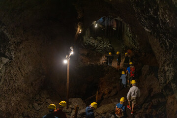Group exploring a volcanic cave in the Volcanic Caves Park at the foot of Villarrica volcano in...