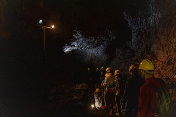 Group exploring a volcanic cave in the Volcanic Caves Park at the foot of Villarrica volcano in...
