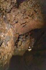 Exploring a volcanic cave in the Volcanic Caves Park at the foot of Villarrica volcano in Pucon, Chile 