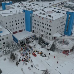 Borovlyany, Belarus - 18.12.2022: Charity event: Santa Clauses-alpinists descend from the roof to wish New Year and Merry Christmas to children in the cancer center and give them gifts