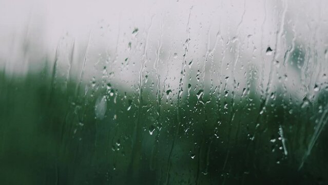 Rain slowly dripping down from the window, a cinematic effect 