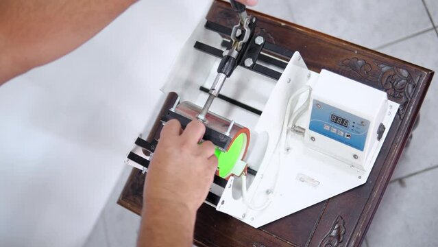 Man making thermal transfer print on green coffee mug, cup print concept