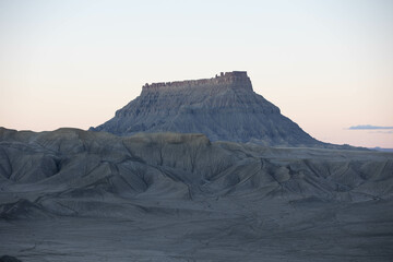 Factory Butte in Caineville, Utah at sunset surrounded by bentonite hills