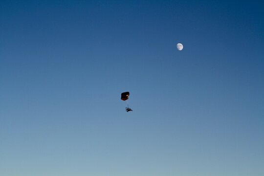 Powered Parachute flying against blue sky and moon