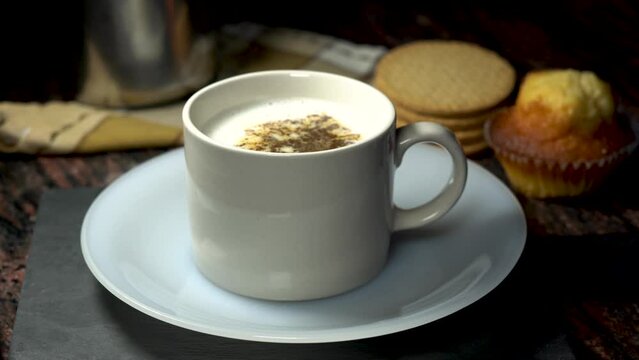 A person adds instant coffee to hot milk in a mug