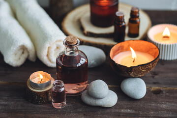 Concept of natural essential organic oils, Bali spa, beauty treatment, relax time. Atmosphere of relaxation, pleasure. Candles, towels, dark wooden background. Alternative oriental medicine