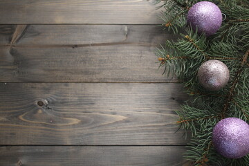 Christmas tree branch background with festive balls of purple silver color against a black tree background with space for copyspace text