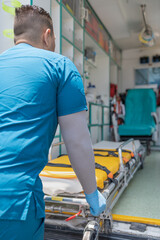 Vertical photo of a doctor using a stretcher from an ambulance outdoors