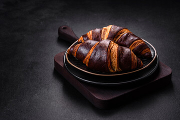 Beautiful tasty fresh crispy croissant on a dark concrete background