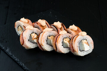 Set of sushi rolls with raw sea bass fish, cream cheese, smoked bacon and sauce.
