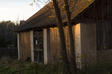 Stara stodoła murowana i z drewna , o dachu pokrytym betonowymi ( cementowymi ) dachówkami . Jesień - zachód słońca .