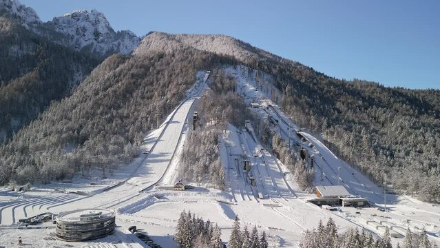 Orbit movement of ski Jump in Planica near Kranjska Gora Slovenia covered in snow at winter time, aerial view.