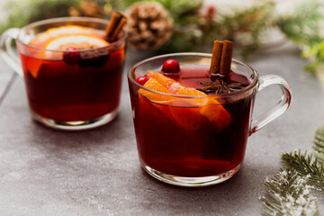 Two cups of christmas mulled wine or gluhwein with spices and orange slices on rustic table top view.