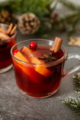 Two cups of christmas mulled wine or gluhwein with spices and orange slices on rustic table top view.