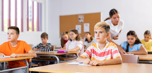 Schoolboy sitting at the desk in classroom at lesson in primary school