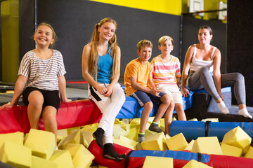 Cheerful friends, preteen girls and boys, enjoying spending time together in indoor inflatable...
