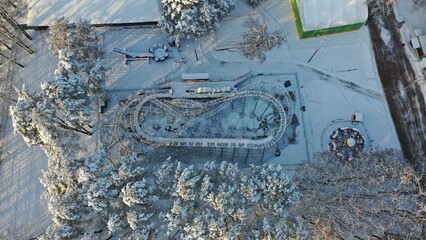 Roller coaster in the snow. Amusement park under ice and snow. Global cooling. Attractions in the park under the snow in winter. City park in winter.