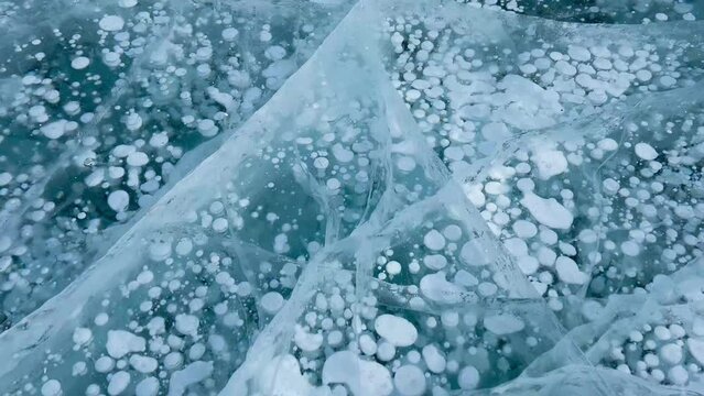 Frozen methane bubbles and cracks in the ice on Lake Baikal Siberia Russia. Natural cold background of ice. Winter abstract background. High quality 4k footage
