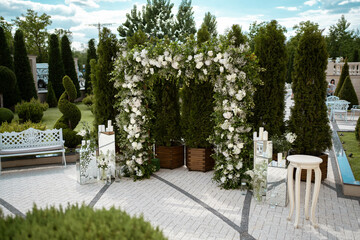 Wedding. Wedding ceremony. Arch. Arch, decorated with white flowers standing in the woods, in the wedding ceremony area.