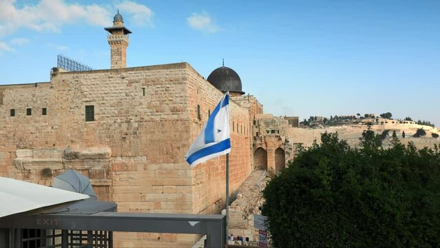 the old city in Jerusalem with a view of the Israeli flag fluttering in the wind above the entrance to the wailing wall