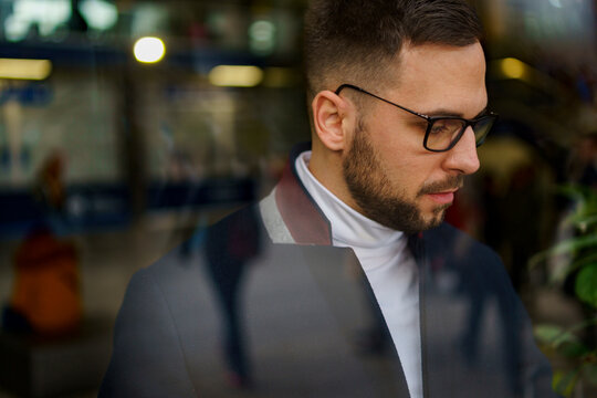 portrait of an attractive man wearing glasses and a turtule neck, shot through the window
