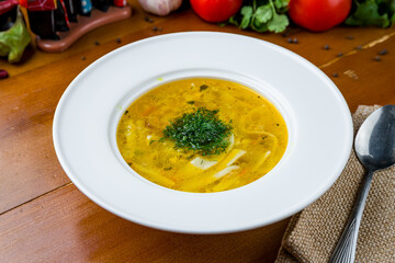 Chicken soup bouillon in a plate on wooden table