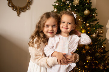 Merry Christmas and Happy Holidays. Smiling girls playing with a Christmas decoration, Christmas tree on the background