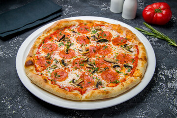 Pepperoni pizza with mushrooms on dark table