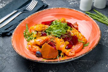 salad with shrimp, avocado, orange and strawberries on black table