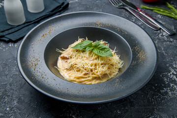 Spaghetti Carbonara with bacon on dark table