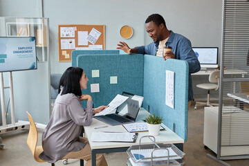 Side view portrait of two colleagues chatting in office over partition wall, copy space