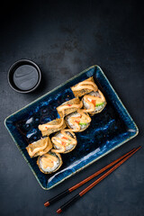 Set of tempura sushi rolls with salmon fish, cream cheese, avocado and sauce.