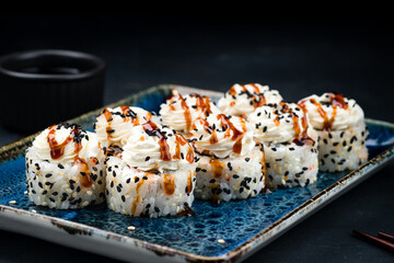 Sushi rolls with tuna, cream cheese, avocado in sesame seeds and sauce.