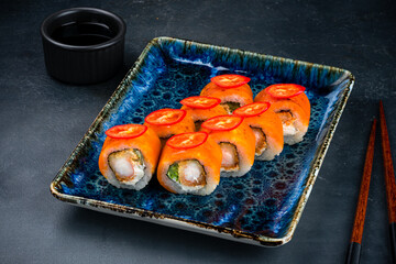 Set of sushi rolls with shrimp tempura, cream cheese, lettuce, cheddar cheese, chili peppers, soy sauce and chopsticks.