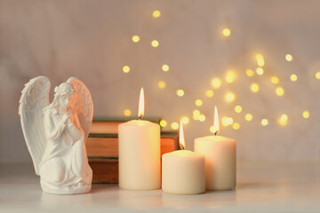 praying angel and candles on table close up, abstract light background. Christmas or Easter holiday...