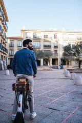 Young man in denim jacket sitting atop his vintage classic bicycle looking out over the city.