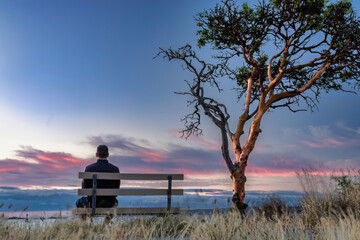 Fototapeta na wymiar Man on bench reflecting in Nanaimo sky