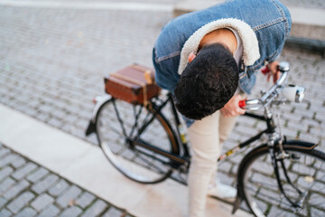 Obraz premium Young man in denim jacket looking at what is happening on his vintage classic bike.