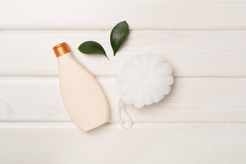 Shower gel with washcloth on wooden background, top view