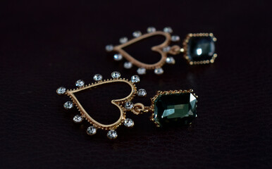 Fototapeta na wymiar Gold earrings decorated with green gems. that shines beautifully