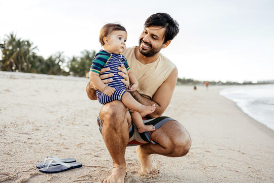 A young father and his baby son spending quality time at the beach