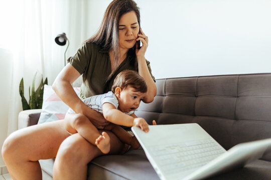 A busy mother tries to work from home with her baby son