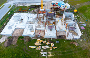 Modern commercial building under construction, with crane and other building equipment, top down view