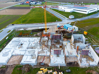 Modern commercial building under construction, with crane and other building equipment, top down...