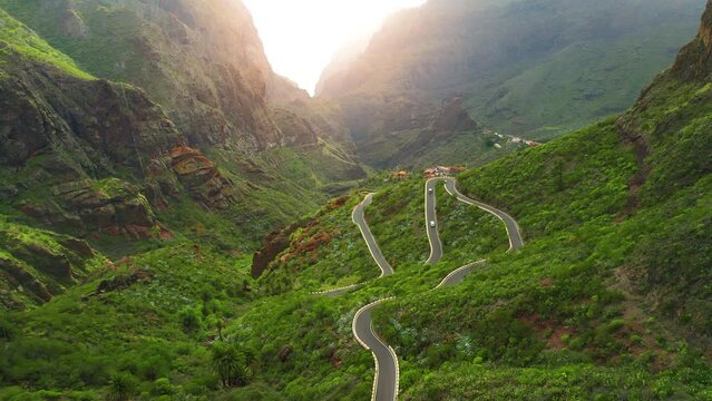 Day glow green mountain landscape in Masca Gorge and small village in ravine during sunrise. Magical sun glare on rock tops. Tenerife Canary Islands Spain Europe.