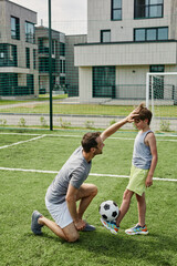 Vertical portrait of loving father and son playing football together at outdoor court