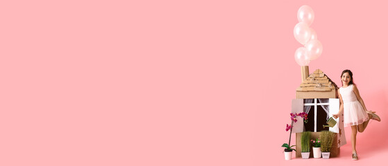 Funny little girl playing with cardboard house on pink background with space for text
