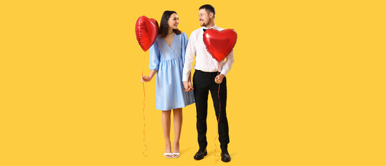 Happy couple with balloons in shape of hearts on yellow background. Valentine's Day celebration © Pixel-Shot