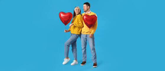 Happy couple with balloons in shape of hearts on light blue background. Valentine's Day celebration